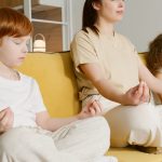 Family practicing meditation together on a couch, promoting mindfulness and relaxation.